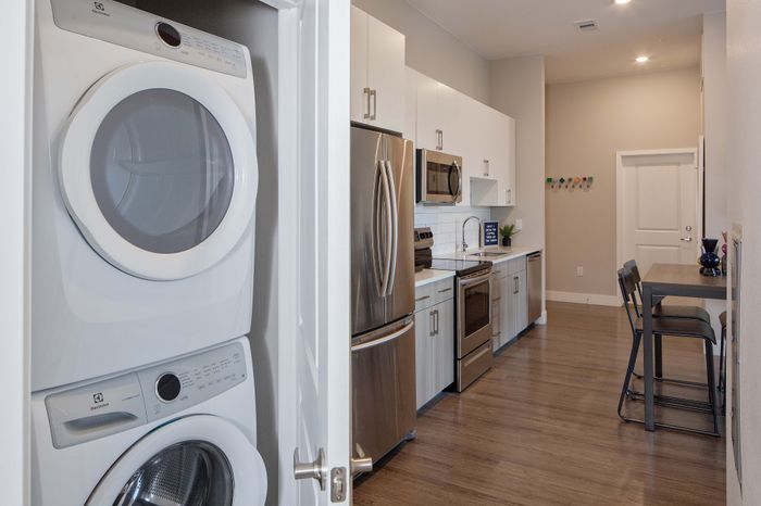 Modern apartment kitchen with sleek stainless steel appliances and convenient in-unit washer and dryer.
