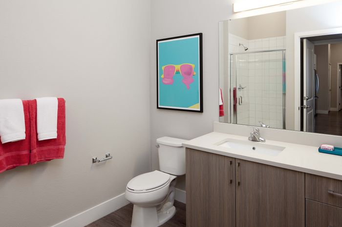 Modern bathroom with sleek vanity, stylish wall art, and vibrant red towels, exuding a fresh and inviting ambiance.