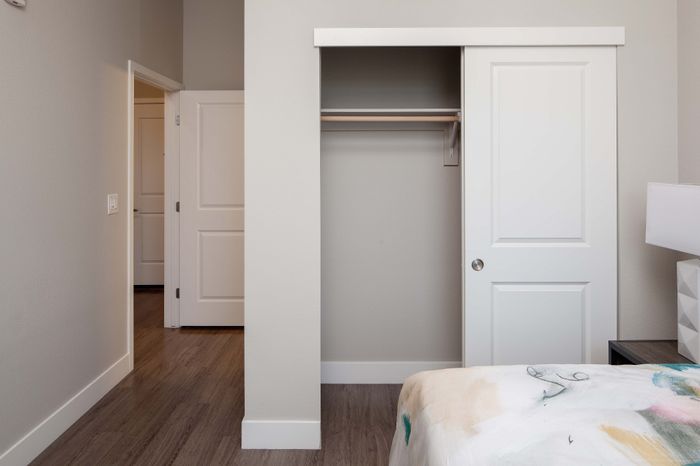Modern bedroom with sleek sliding closet doors, elegant gray walls, and stylish wood flooring.