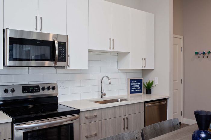 Modern kitchen with sleek white cabinets, stainless steel appliances, and a minimalist design, perfect for stylish living.