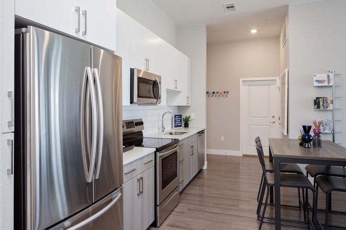 Modern kitchen with sleek stainless steel appliances, stylish cabinetry, and a chic dining area on hardwood floors.
