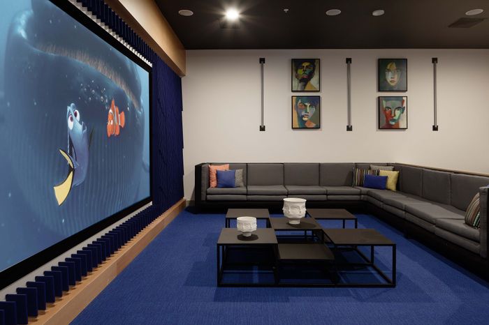 Contemporary entertainment room featuring a cozy L-shaped sofa, vibrant blue carpeting, and a large movie screen, ideal for family gatherings and movie nights.