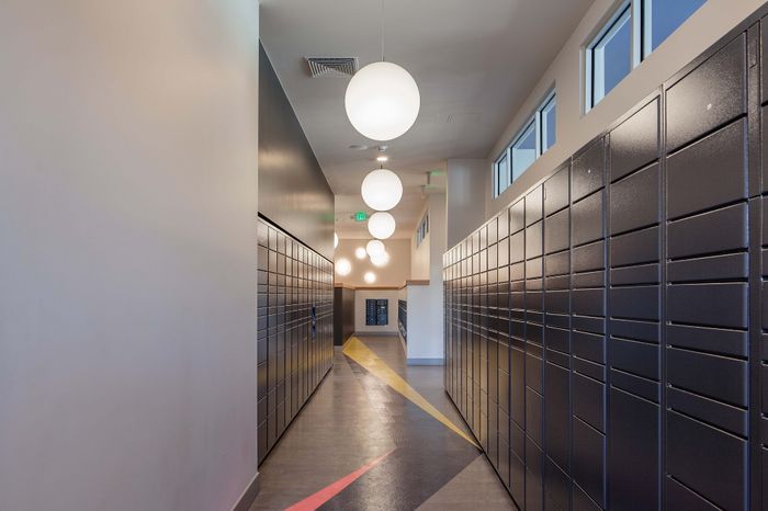 Contemporary hallway with sleek black mailbox lockers, modern lighting, and geometric floor design.