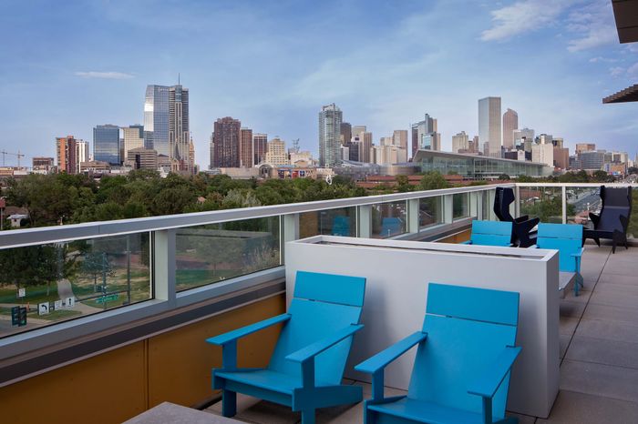 Modern balcony with vibrant blue seating offering breathtaking views of a dynamic city skyline.
