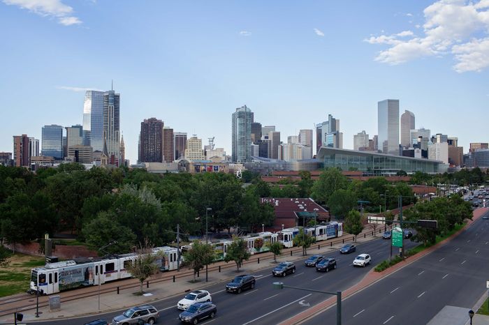 Vibrant urban skyline featuring modern skyscrapers and lush green parkland, with a sleek tram adding a dynamic touch to the bustling cityscape.