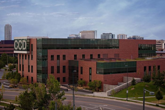 Modern brick and glass building with lush greenery, situated in an urban environment, perfect for business or educational purposes.