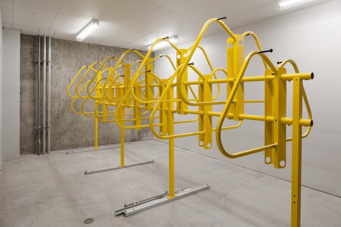 Modern indoor bike storage room with vibrant yellow racks, offering convenient and stylish parking for bicycles.
