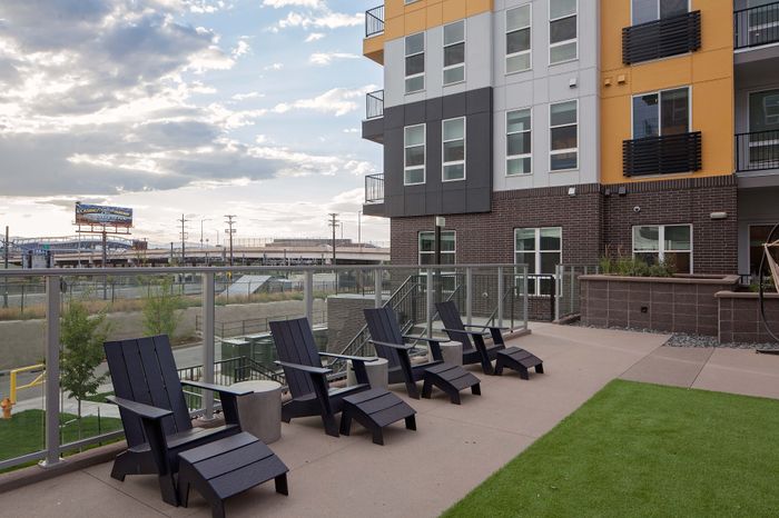 Modern apartment exterior with stylish patio chairs, lush greenery, and contemporary architecture, perfect for relaxation and social gatherings.