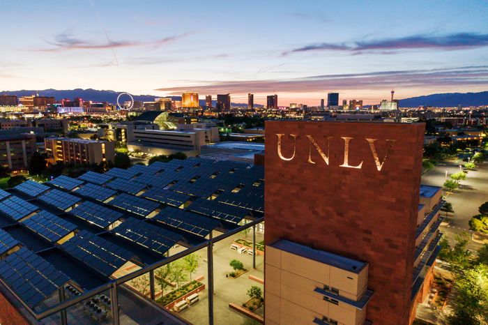Dazzling evening view of a vibrant city skyline from a rooftop, showcasing stunning architecture and a warm sunset glow.