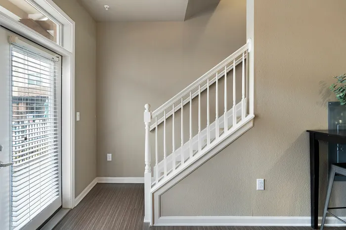 Bright entryway with elegant white staircase and large window, providing a welcoming and airy ambiance.