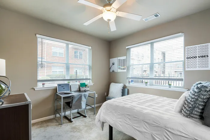 Bright and cozy bedroom with stylish decor, featuring a comfortable bed, a sleek desk, and large windows for ample natural light.
