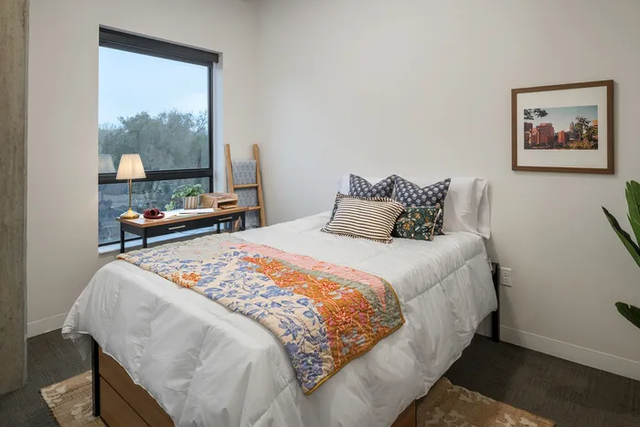 Cozy and bright bedroom featuring elegant bedding, large window with scenic view, and stylish decoration.