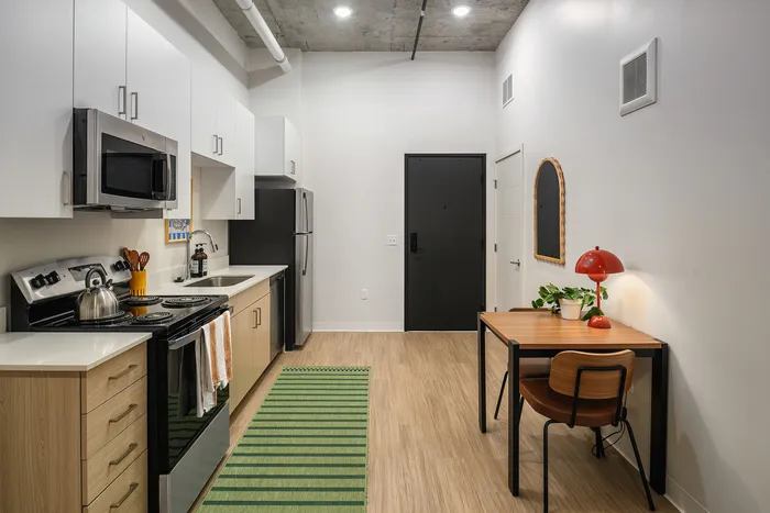 Modern kitchen with sleek cabinetry, stainless steel appliances, and a cozy dining area, perfect for stylish urban living.