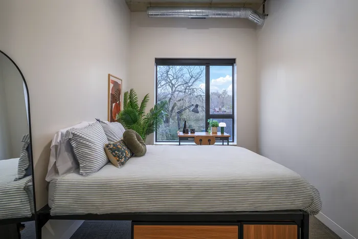 Cozy bedroom with large window showcasing a tranquil view, stylish decor, and ample natural light.