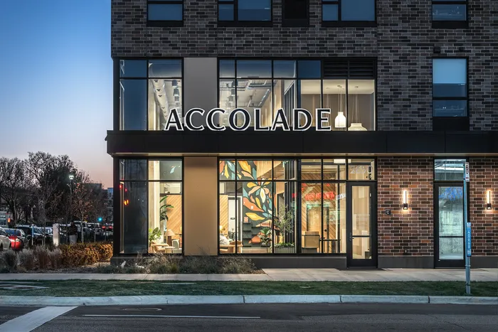 Chic and modern building facade with large windows and the illuminated 'ACCOLADE' sign, showcasing a stylish and inviting interior.