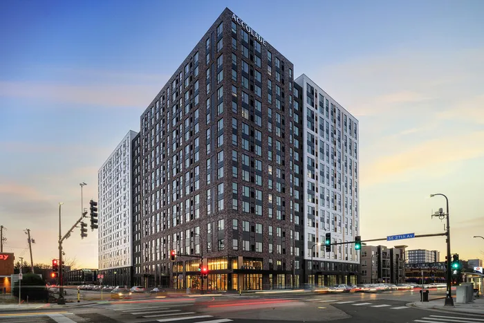 Stunning modern high-rise apartment building with sleek architecture and urban appeal, set against a vibrant cityscape at dusk.