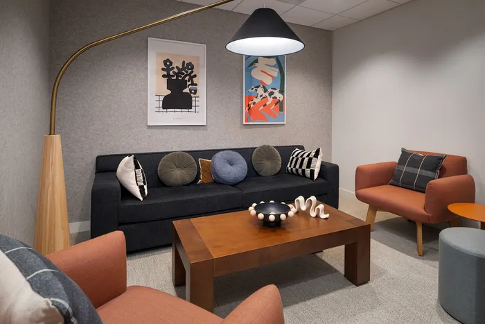 Contemporary living room with stylish furniture, featuring a plush dark sofa adorned with decorative pillows, two modern art pieces, and a chic wooden coffee table with unique decor accents.