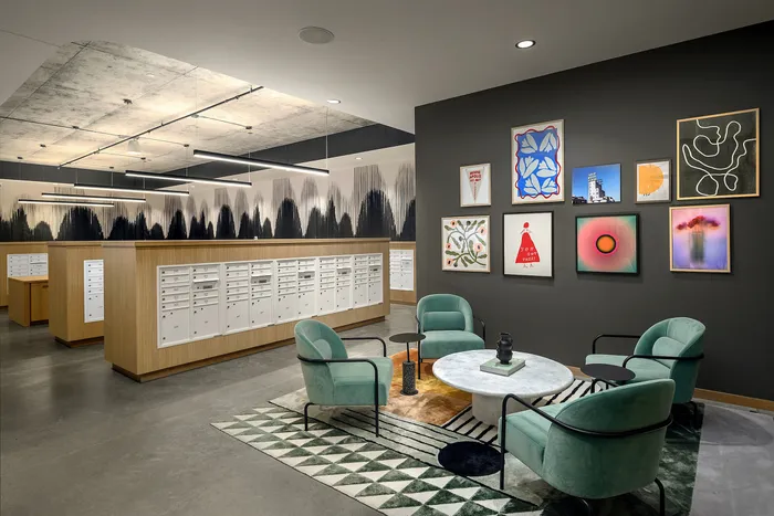 Modern lobby area with vibrant teal chairs, a sleek round table, and eye-catching wall art, perfect for a stylish living experience.