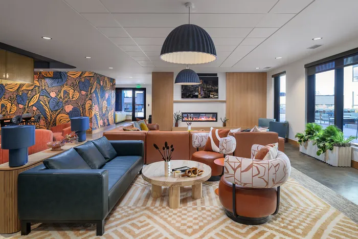 Chic, modern living space with vibrant floral wallpaper, stylish furniture, and large windows offering natural light.