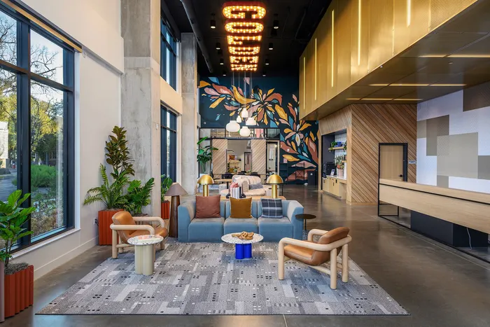 Modern apartment lobby with chic seating area, vibrant mural, and large windows inviting natural light.
