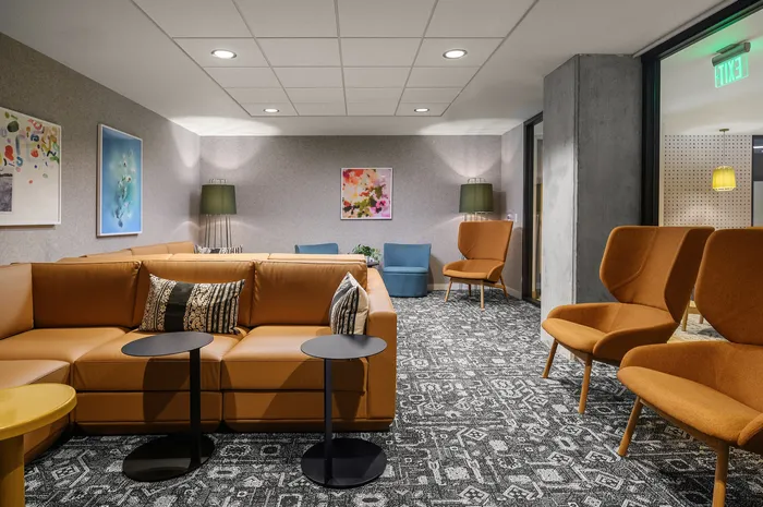 Chic apartment lounge with modern seating, vibrant art, and patterned carpet, creating a sophisticated and welcoming atmosphere.