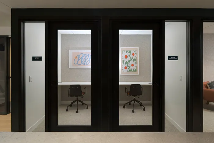 Modern dual study rooms with sleek glass doors, stylish art, and ergonomic chairs for a productive workspace.