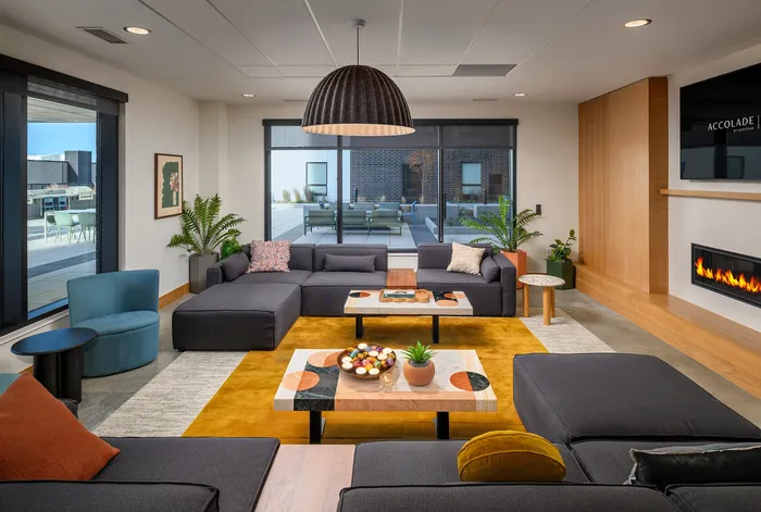 Modern living room with spacious L-shaped sofa, vibrant artwork, lush green plants, and cozy fireplace, creating a warm and inviting ambiance.