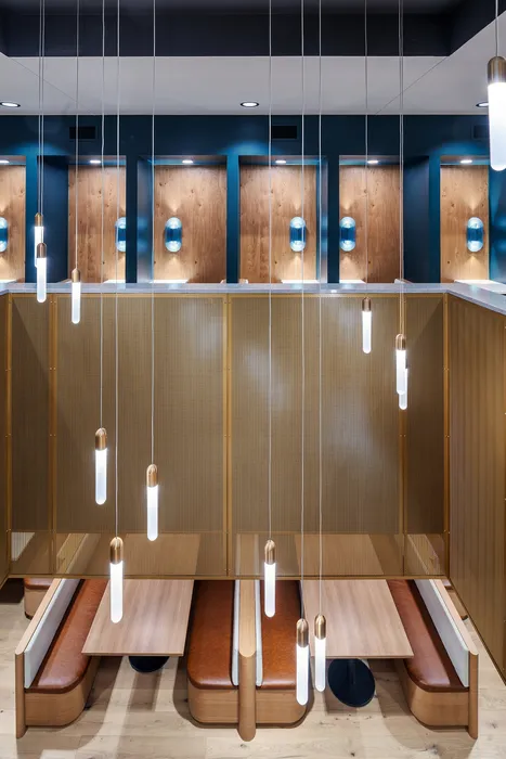 Chic modern dining area featuring sleek pendant lighting, elegant wood accents, and cozy upholstered seating.