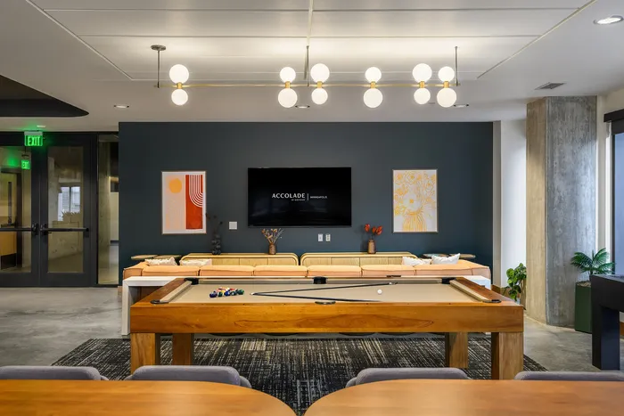 Inviting modern lounge with a luxurious pool table, chic lighting, cozy sofa, and elegant wall art, perfect for social gatherings.