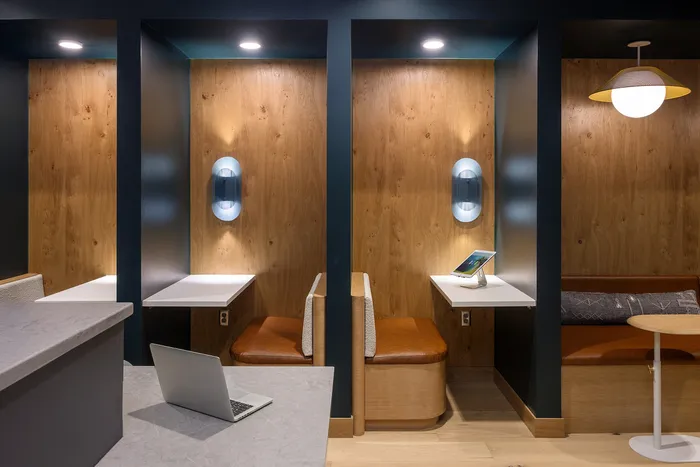 Cozy modern workspace with stylish wooden accents, featuring two comfortable nooks with built-in seating, ambient lighting, and sleek tablet display.