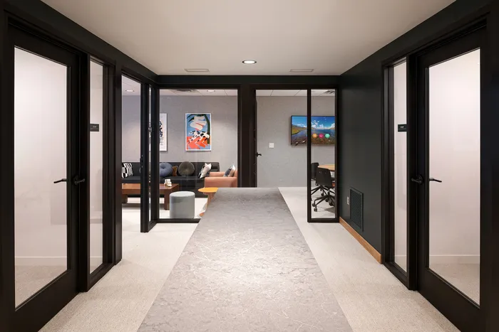 Modern office space featuring glass panel doors, a stylish lounge area with artwork, and a conference room with advanced technology.