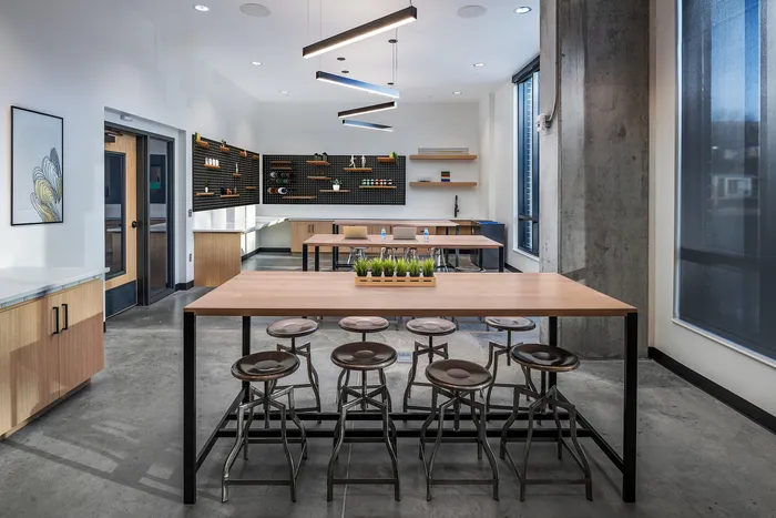 Contemporary communal kitchen with stylish wooden countertops, trendy bar stools, and sleek shelving on a backdrop of modern industrial design.