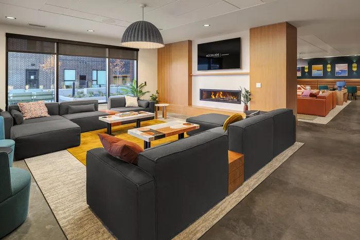 Modern communal lounge area featuring sleek seating, a cozy fireplace, and large windows offering natural light.