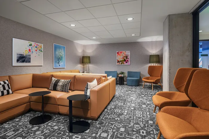 Chic and comfortable lounge area featuring a stylish L-shaped leather sofa, modern art pieces, and cozy seating options with vibrant accent chairs.