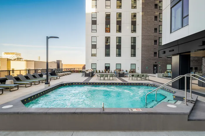 Luxurious outdoor pool area with stylish lounge chairs and modern high-rise building backdrop, perfect for relaxation and entertainment.