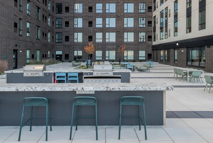 Contemporary apartment courtyard featuring stylish outdoor seating, sleek grilling stations, and vibrant greenery for relaxed socializing.
