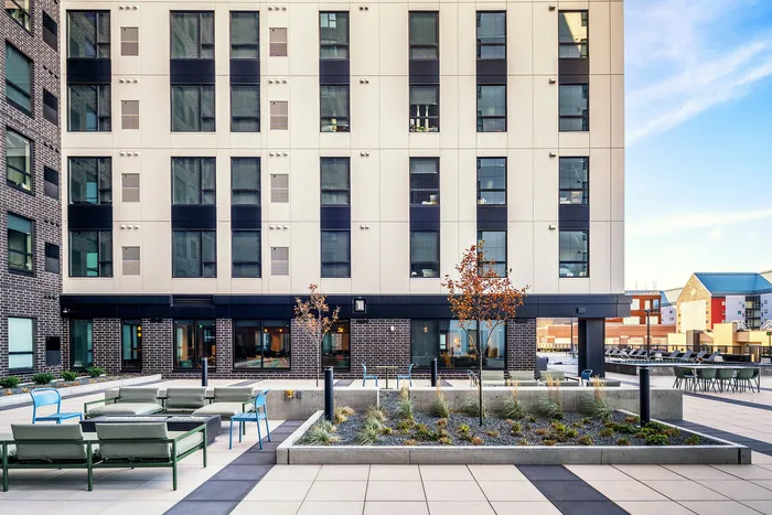 Modern urban apartment building with chic outdoor seating area and stylish landscaping.