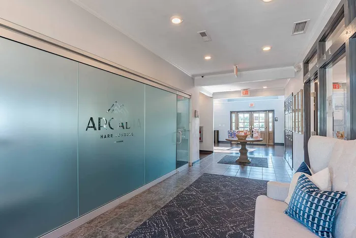 Welcoming and modern apartment lobby with frosted glass doors, stylish seating, and elegant decor.