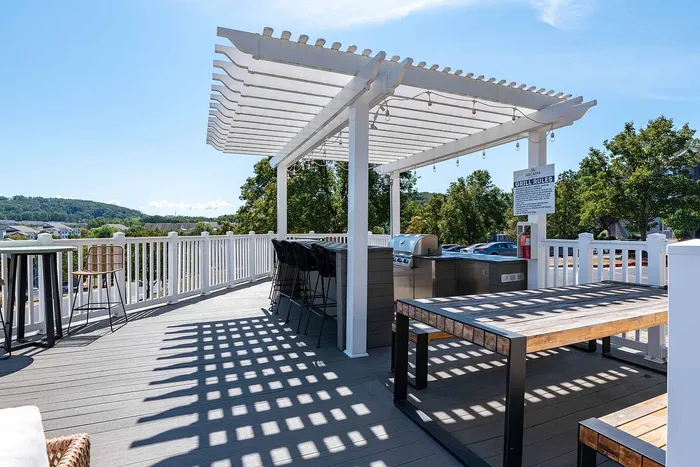Inviting outdoor deck featuring a modern pergola, barbecue grill, and stylish seating with scenic views.