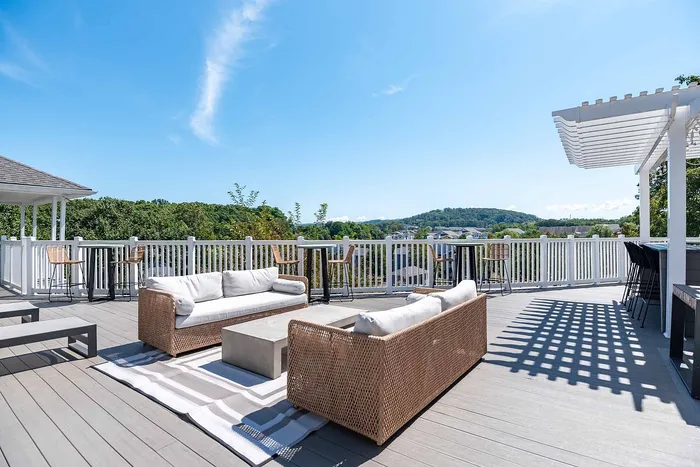 Elegant rooftop deck with comfortable wicker seating, scenic views, and a stylish pergola.