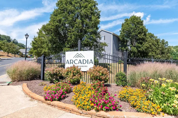 Charming entrance of Arcadia with vibrant garden blooms and lush greenery in a serene neighborhood setting.