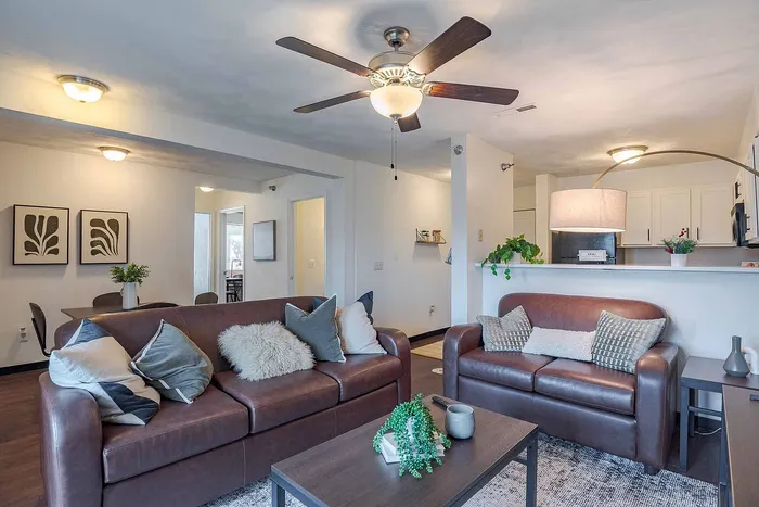 Inviting and modern living space featuring plush leather sofas, chic decor, and a sleek open kitchen, perfect for entertaining.