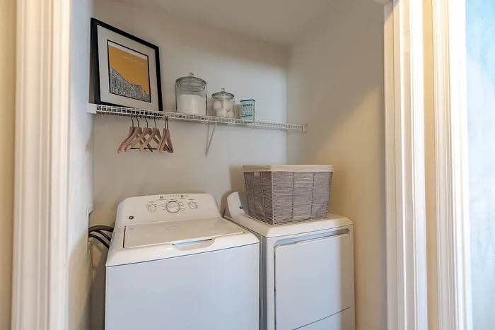 Compact laundry nook featuring a modern washing machine and dryer, complemented by stylish shelving and storage solutions.