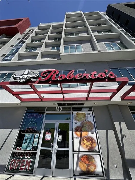 Modern apartment building with an inviting restaurant on the ground floor, featuring large windows and appealing architectural design.