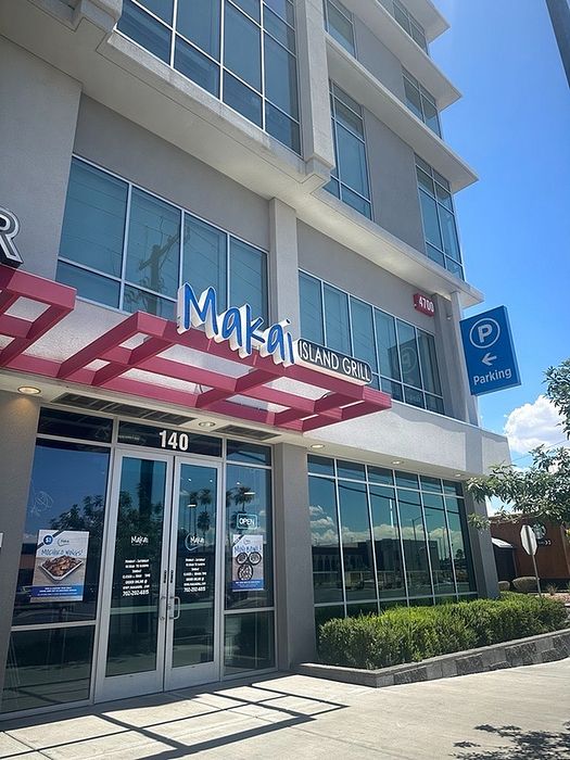 Chic modern building exterior with large windows, featuring a vibrant sign for Makai Island Grill, located next to convenient parking.