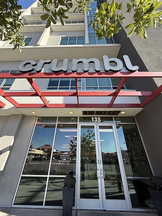 Contemporary building exterior with large windows and bold red accents, featuring the inviting entrance of a popular dessert shop.