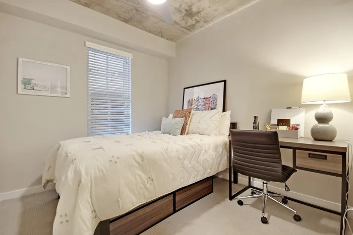 Cozy bedroom featuring a stylish bed with elegant bedding, paired with a sleek desk and contemporary chair, creating an inviting and modern space.
