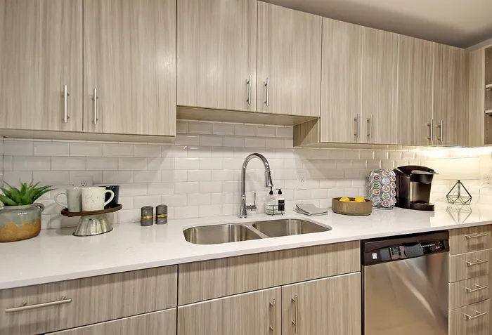 Modern kitchen with sleek cabinets, glossy subway tile backsplash, and stainless steel appliances, offering a stylish and functional space.