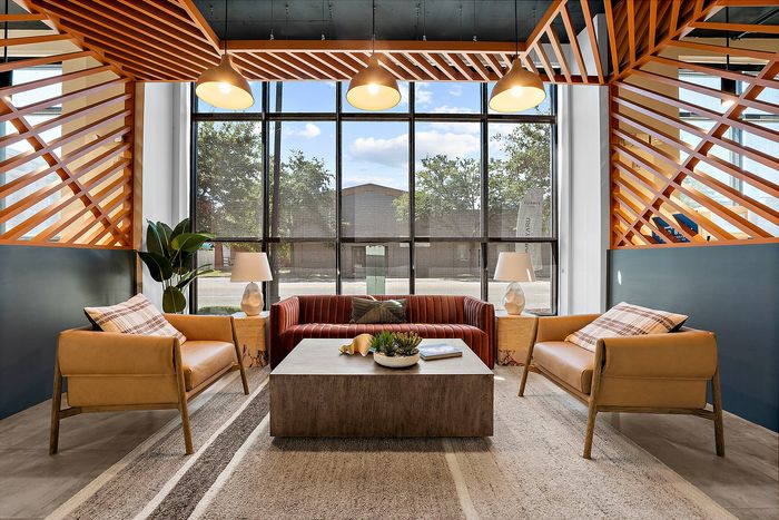 Elegant living room with stylish geometric wooden ceiling design, cozy seating, and large windows offering a bright, airy ambiance.