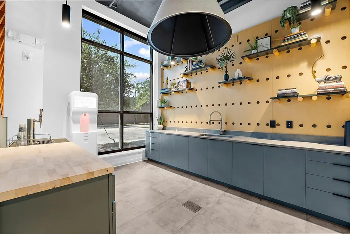Chic modern kitchen featuring sleek cabinetry, stylish open shelving with decor, and a large window for natural light.